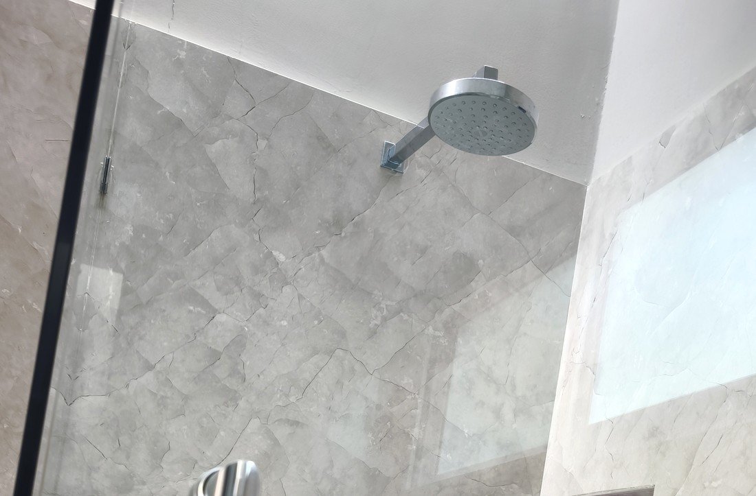 Cancel de cristal limpio y regadera sin sarro en un baño con equipo antisarro DESINCAL instalado