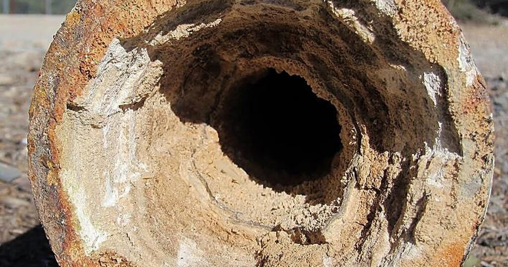 Interior de una tubería casi obstruida por sarro: la incrustación de calcita redujo el diámetro útil